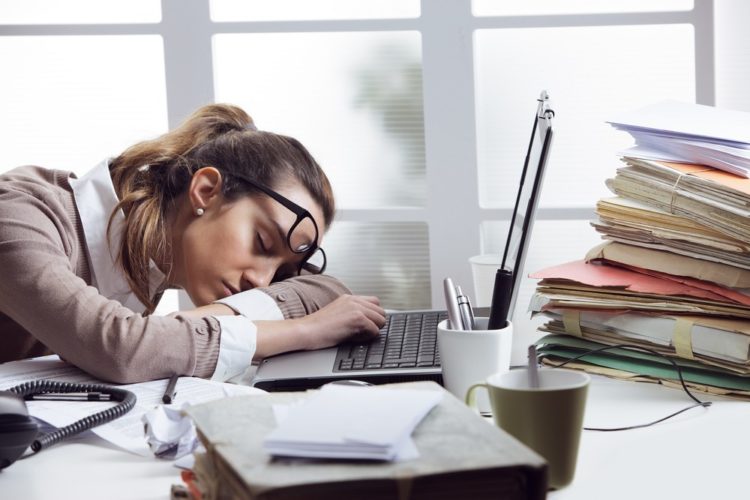 Tired woman asleep at messy desk