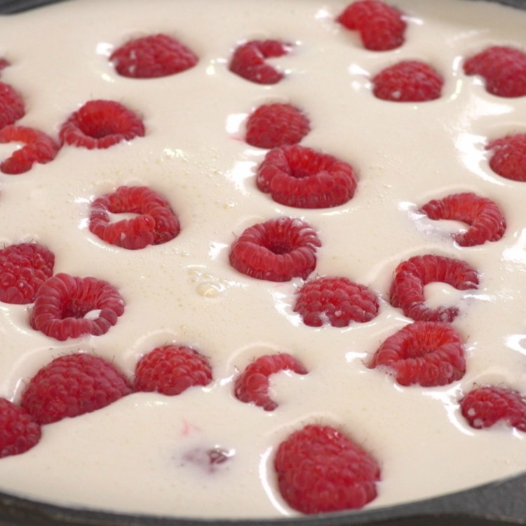 Putting raspberries in custard before baking clafoutis