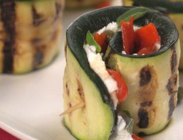 Close-up of grilled zucchini rolls with goat cheese, capers and peppers