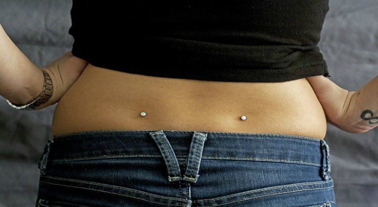 Person with back dimple piercings.