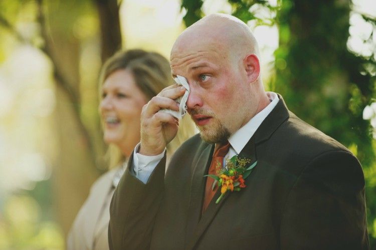 Groom wiping tears from face.