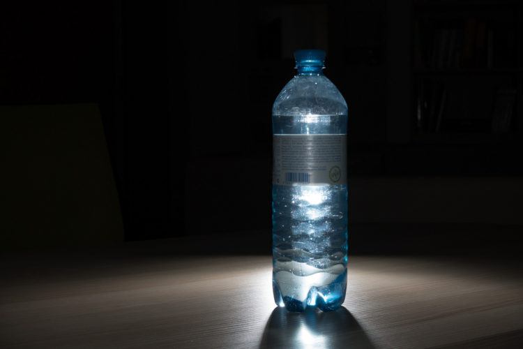 glowing blue water bottle on black background