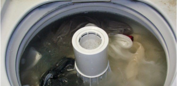 open washing machine filled with water and clothes