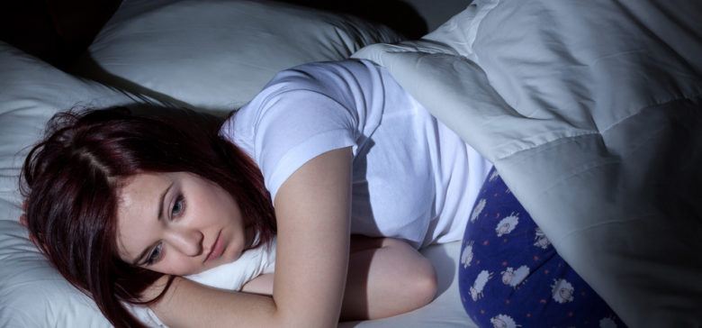 Woman stays up in bed unable to sleep.
