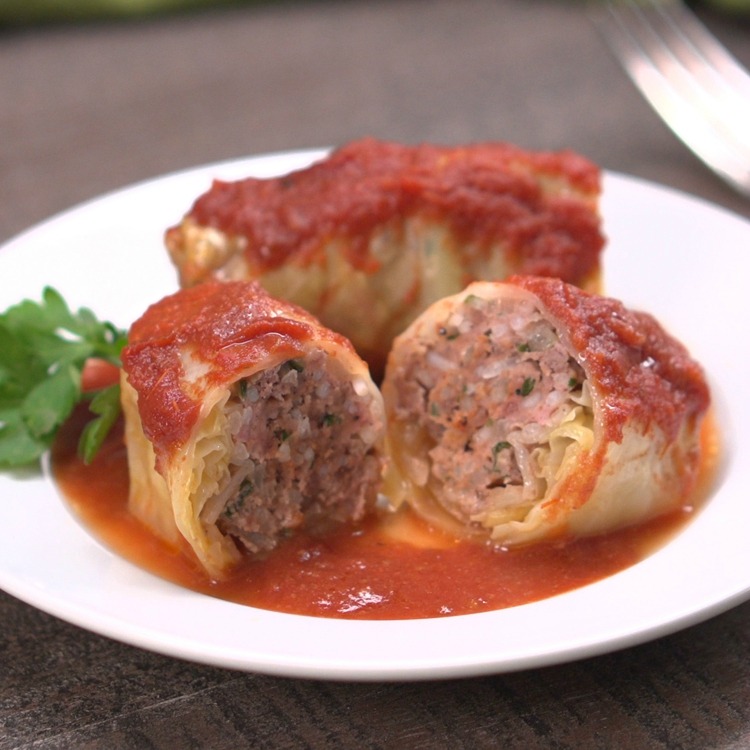 Cabbage rolls on white plate, 1 cut in half