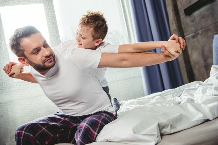 Father and son in pajamas on bed