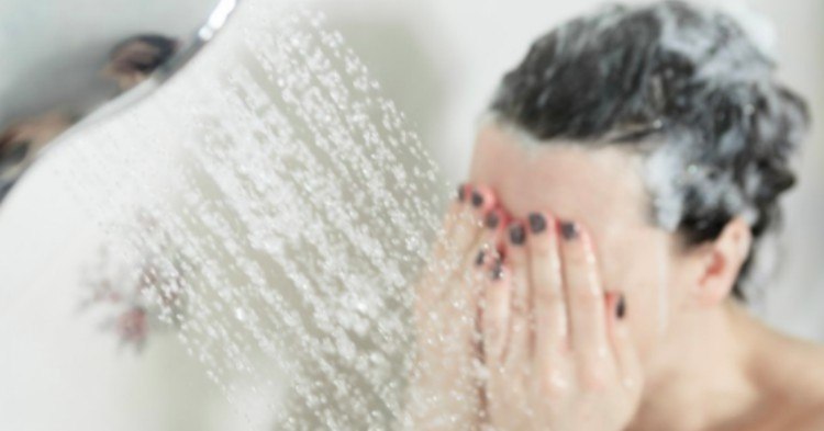 woman covers face in shower