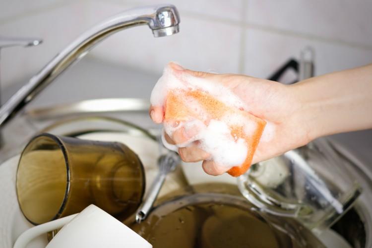 Image of woman doing dishes with sponge.