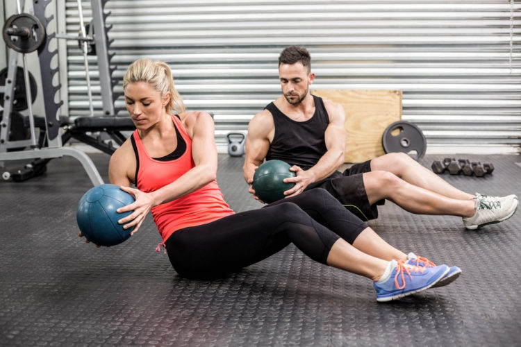 Fit couple doing abdominal ball exercise at crossfit gym