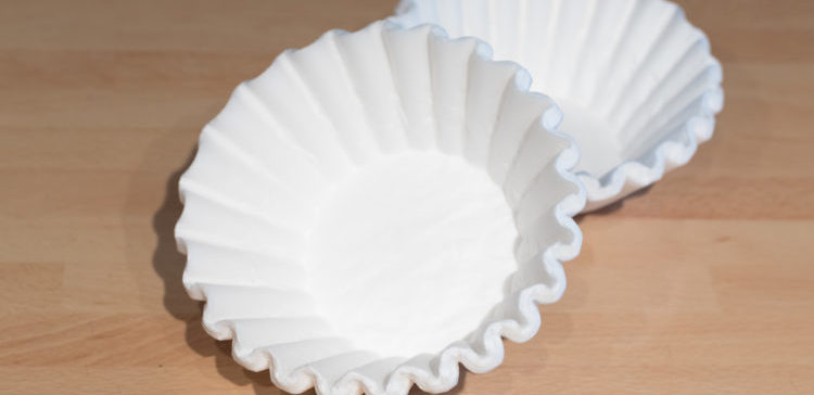 Image of white coffee filters on a wooden table.