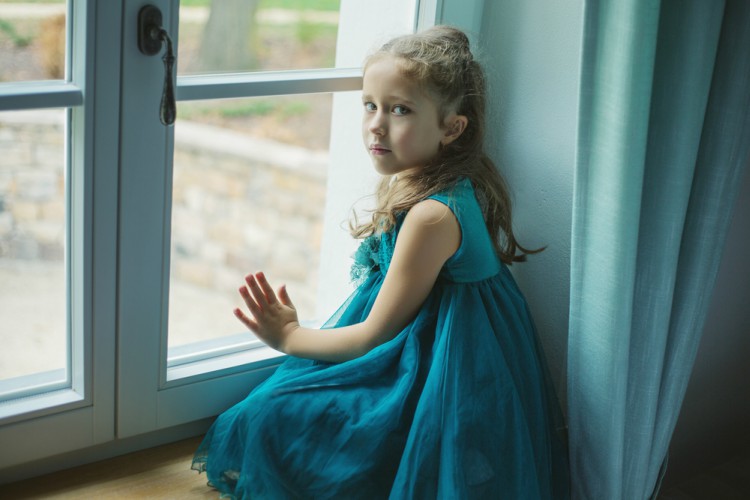 Image of sad girl looking out window.