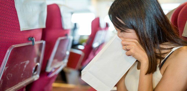 Image of sick woman with barf bag on airplane.