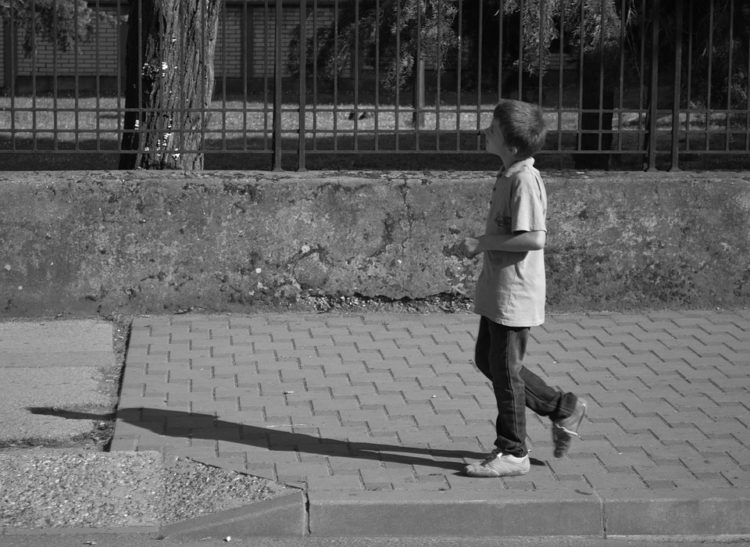 Image of boy walking alone, black and white.