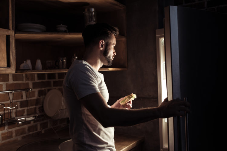 Image of man looking into refrigerator at night
