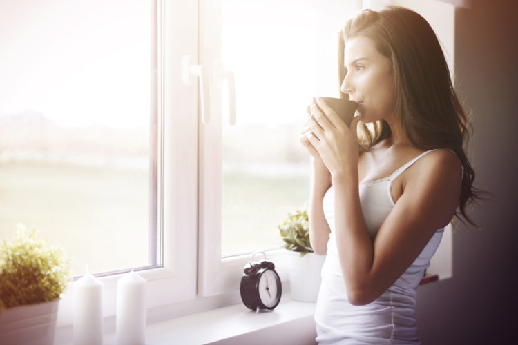 Image of woman drinking coffee by a window