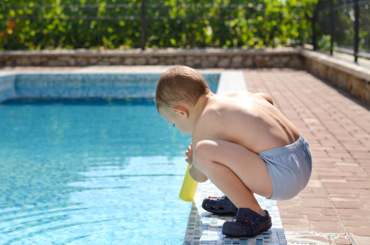 Image of young boy playing at the edge of a swimming pool