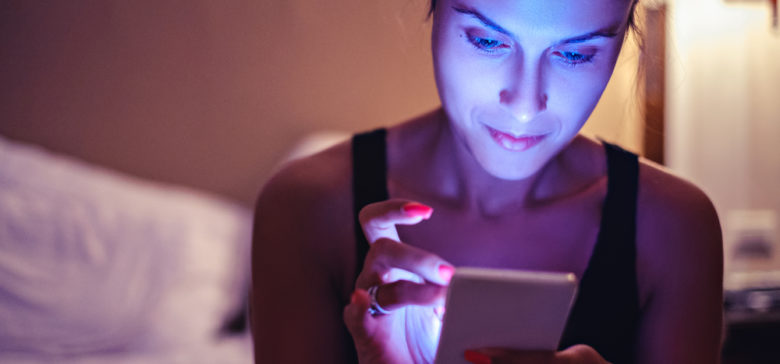 Image of girl looking at mobile phone in the dimmed bedroom