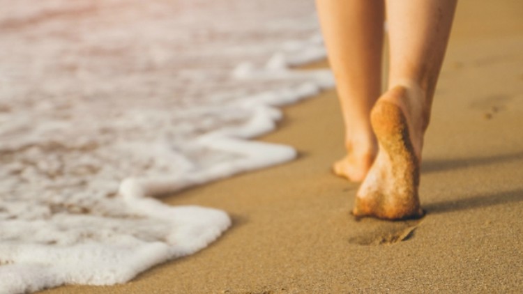 Image of feet walking on sand at the beach