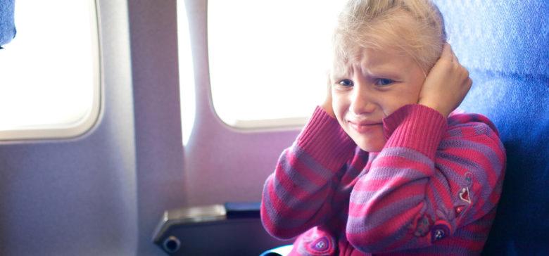 girl plugs ears on plane