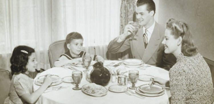 Black and white photo of family eating dinner.