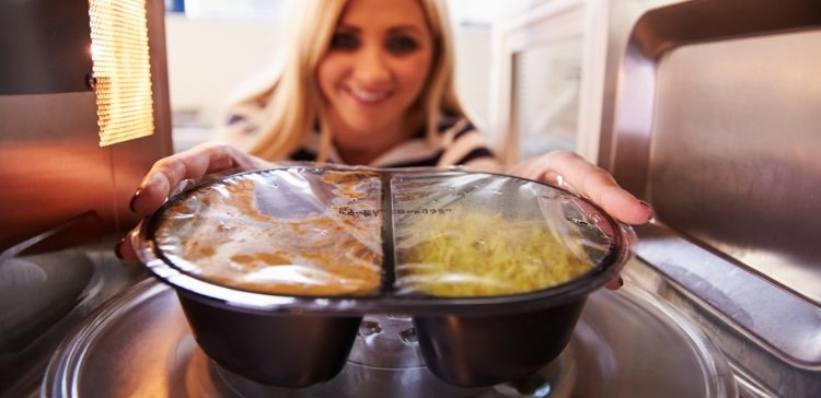Image of woman microwaving leftovers in palstic