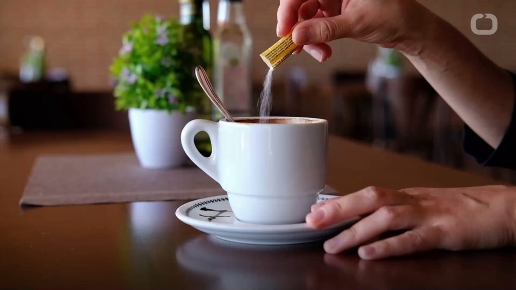 packet of sugar being poured into coffee