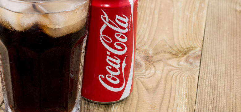 Image of coca cola can with Cola in a glass in wooden background