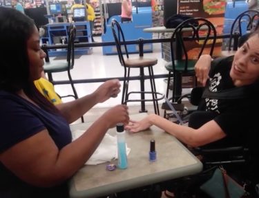 Image of Walmart employee painting woman with cerebral palsy's nails