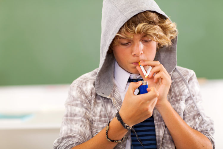 Image of teen boy lighting a cigarette