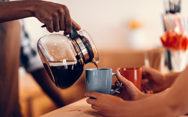 Black coffee being poured into mug.