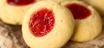 Image of Thumbprint Christmas cookies filled with strawberry jam, photographed with natural light (Selective Focus, Focus diagonally through the cookie)