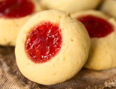 Image of Thumbprint Christmas cookies filled with strawberry jam, photographed with natural light (Selective Focus, Focus diagonally through the cookie)