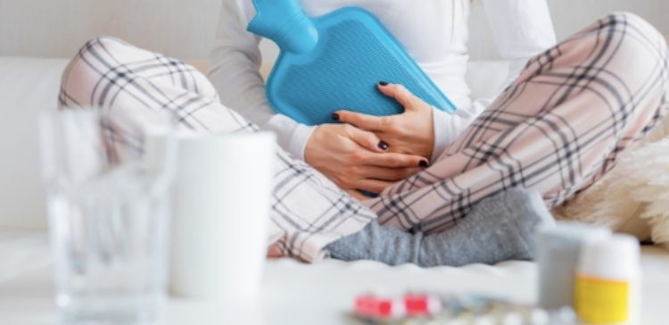 woman holds hot water bottle to stomach