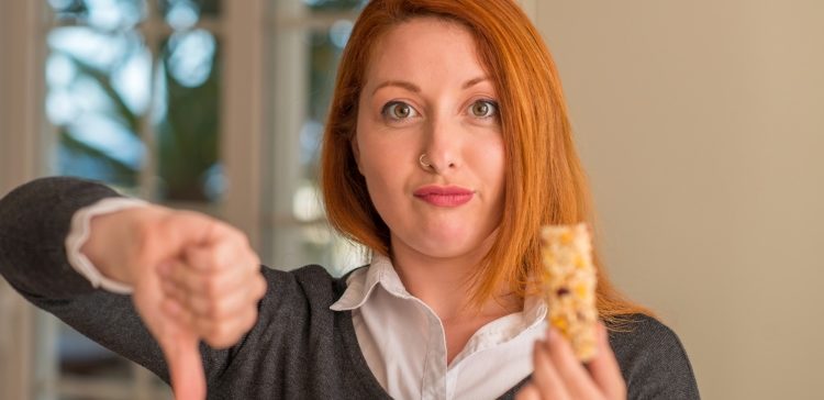 Image of redhead girl with cereal bar with a thumbs down