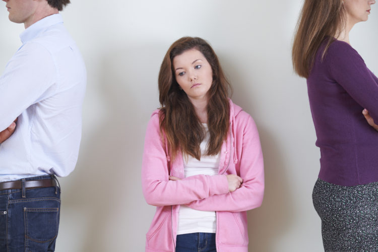 Image of Teenage Girl Standing Between Parents Not Speaking To Each Other